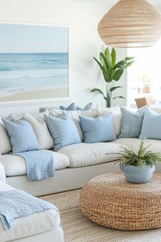 a living room filled with white furniture and blue pillows on top of it's couches