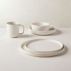 white dishes and cups are arranged on a table top with a cup in the middle