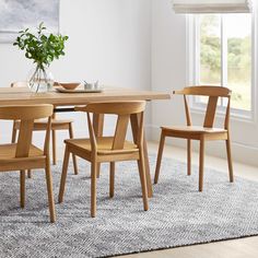 a dining table with four chairs and a bowl of flowers