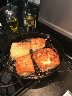 four pieces of food cooking in a skillet on the stove top next to an oven