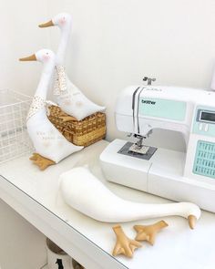 a sewing machine sitting on top of a white table next to a duck statue and basket