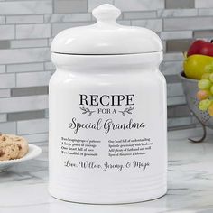 a white cookie jar sitting on top of a counter next to a bowl of fruit