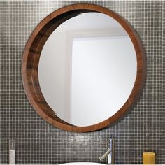 a round mirror hanging on the wall above a sink