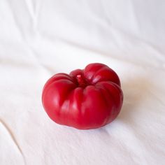 a red tomato sitting on top of a white sheet