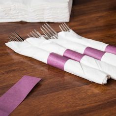 four purple and white striped napkins sitting on top of a wooden table next to a pair of scissors