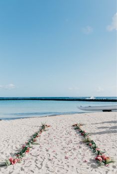 a wedding ceremony setup on the beach with flowers arranged in the shape of a heart