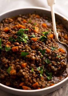 a bowl filled with lentils and carrots on top of a cloth covered table