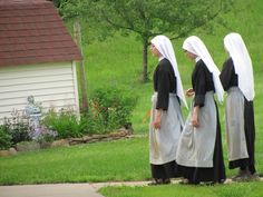 three women dressed in black and white are walking through the grass