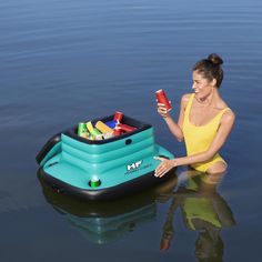 a woman sitting in the water holding a cell phone next to an inflatable raft