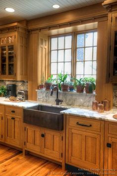 a large kitchen with wooden cabinets and marble counter tops is pictured in this image, there are potted plants on the window sill above the sink