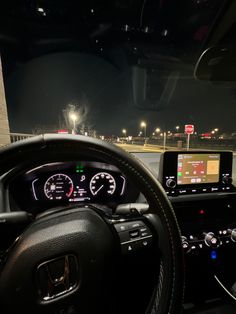 the interior of a car with dashboard lights and electronic gauges on display at night