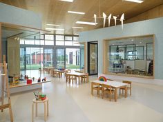 an empty classroom with tables and chairs in front of large windows