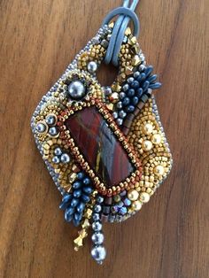 a close up of a piece of jewelry on a wooden surface with beads and pearls