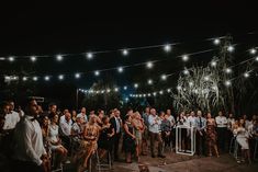 a group of people standing next to each other in front of a crowd at night