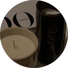 a white candle sitting next to a black container with a vyru logo on it