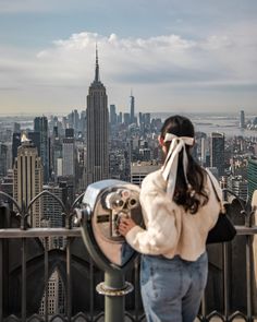 a woman looking through a pair of binoculars at the empire building in new york city