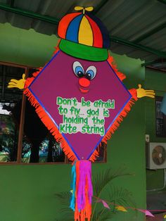 a colorful kite with an image of a clown on it's face that says don't be afraid to fly god is hiding the kite string