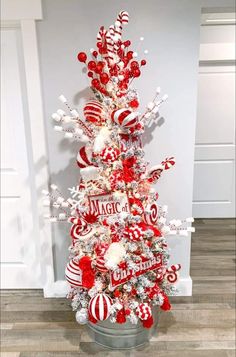 a red and white christmas tree with candy canes on it's branches is in a bucket