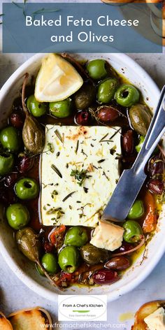 baked feta cheese and olives in a white bowl with bread on the side