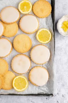 lemon cookies with icing and sliced lemons are on a baking sheet next to an egg