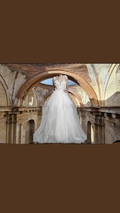 a wedding dress is displayed in an old building with arches and arches on the ceiling