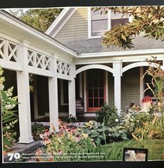 the front porch is covered with white pillars and columns, along with flowers in the foreground