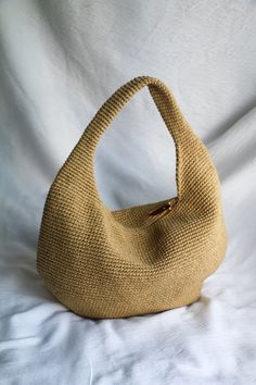 a beige purse sitting on top of a white sheet