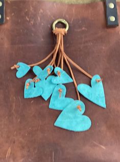 several pieces of blue leather are hanging from a string on a piece of brown leather