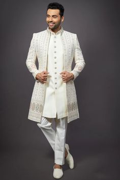 a man in a white sherwa with his hands on his hips, posing for the