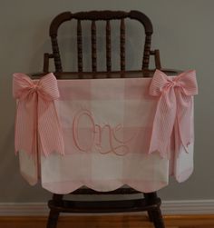 a pink and white gingham chair cover with the word one written on it