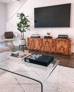 a living room with a glass coffee table and a television mounted on the wall above it