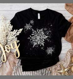 Wear this snowy tee through Christmas, New Years, and the rest of the winter season! This snowflakes t-shirt features beautiful,  falling snow. A great gift for winter sports enthusiasts! Everyone needs the perfect t-shirt to complement an everyday, laid-back look. The ideal top for so many occasions, this lightweight cotton tee will keep you comfy and looking smart. * 100% combed and ring-spun cotton (Heather colors contain polyester) * Fabric weight: 4.2 oz/yd² (142 g/m²) * Pre-shrunk fabric * Side-seamed construction * Shoulder-to-shoulder taping * Blank product sourced from Guatemala, Nicaragua, Mexico, Honduras, or the US This product is made especially for you as soon as you place an order, which is why it takes us a bit longer to deliver it to you. Making products on demand instead Black Shirt For Winter Holiday, White Graphic Tee For Winter, Black Winter Holiday T-shirt, Short Sleeve Graphic T-shirt For Winter, Winter Graphic Print T-shirt With Short Sleeves, Winter Graphic Print Short Sleeve T-shirt, Graphic Print T-shirt For Gift In Winter, Black Short Sleeve T-shirt For Winter, Holiday Winter Graphic Tee