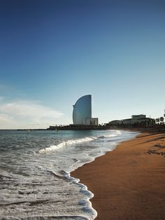 the beach has waves coming in to shore and a large building on the other side