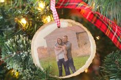 an ornament hanging on a christmas tree with a couple in the center and plaid ribbon around it