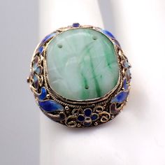 Vintage Chinese silver ring in floral filigree designs with vermeil finish and colorful enamel decorations, featuring carved oval green Jade centerpiece. The size is adjustable. This gorgeous ring is a size 7 1/4 (adjustable), 24 mm at the widest and weighs 6.5 grams. It features some enamel loss. EA2362 White Opal Stud Earrings, Chinese Green, Chinese Greens, Floral Filigree, Gorgeous Ring, Opal Earrings Stud, Opal Studs, Peridot Ring, Filigree Design