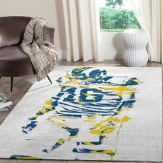 a living room area with a rug and chair in front of the window, featuring a painting of a football player