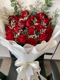 a bouquet of red roses wrapped in white paper and tied to a black tablecloth