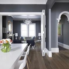 a dining room table with chairs and a vase filled with flowers sitting on top of it