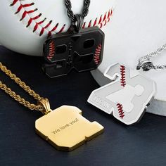 two personalized pendants with baseball bats and ball in the background on a black surface