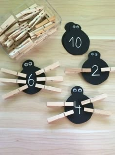 wooden pegs with faces and numbers on them sitting next to a container of clothes pins