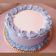 a blue and white cake sitting on top of a pink table cloth covered in gold trim