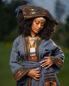 a woman wearing an ethnic dress and headdress with her hands on her hip