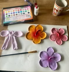 the paper flowers are being made with paint and watercolor pencils, along with other crafting supplies