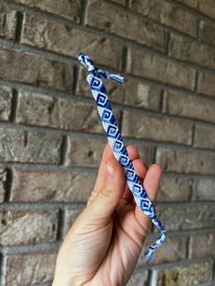 a person holding up a blue and white tie in front of a brick wall,