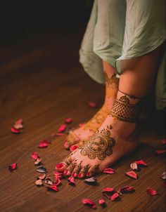 a woman's feet with hennap and rose petals on the floor