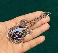 a person is holding a brooch with a guitar on it's back and an arrow in the middle