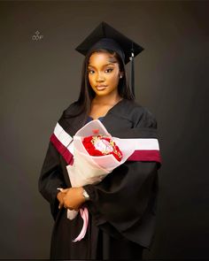 a woman wearing a graduation gown and holding a bouquet