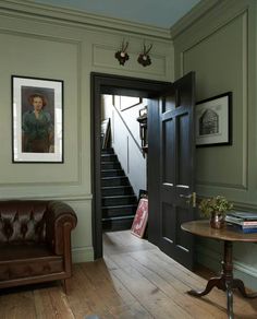 a living room filled with furniture next to a wooden floor and wall mounted pictures on the walls