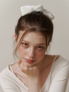 a woman with a white bow on her head looking at the camera while wearing a sweater