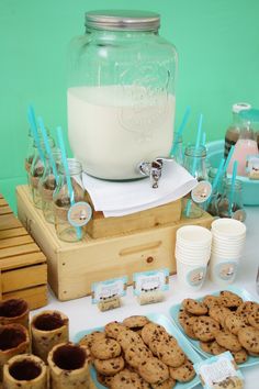 a table topped with cookies and cups filled with milk